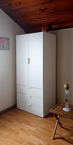 une grande armoire blanche dans une pièce avec une table dans l'établissement Studio aux portes de Paris, très bien desservi par les transports, à Fontenay-sous-Bois