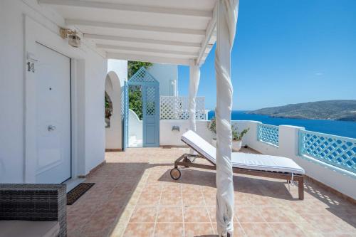 a white porch with a bench and the ocean at Studios Kilindra in Astypalaia Town