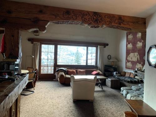 ein Wohnzimmer mit einem Bett und einem großen Fenster in der Unterkunft Chalet mit Blick auf den Gotschna in Klosters