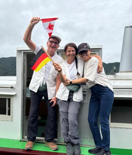 a group of three people standing on a boat with a flag at Hostel John Mang ゲストハウス ジョン in Tosa