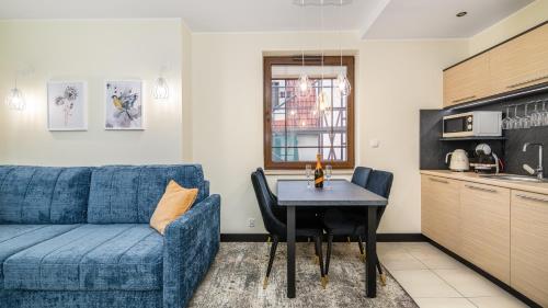 a living room with a blue couch and a table at Apartament Widok Krynica Morska z widokiem na morze in Krynica Morska