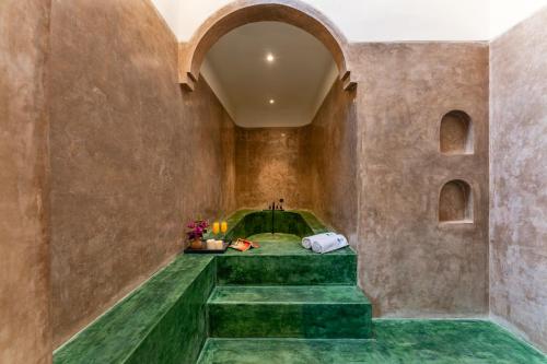a room with green flooring and a stone wall at Villa Lluvia 5bhk-Huge Pvt Pool-Caretaker-Bathtub-Big Garden-Genset Backup- Siolim in Oxel
