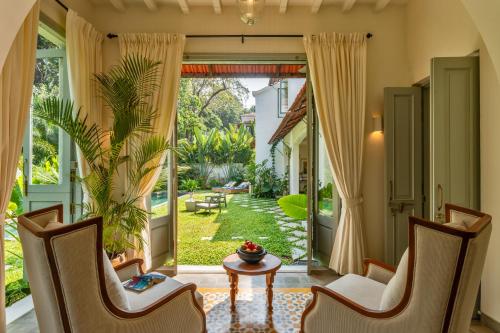 an open door to a garden with chairs and a table at Villa Lluvia 5bhk-Huge Pvt Pool-Caretaker-Bathtub-Big Garden-Genset Backup- Siolim in Oxel