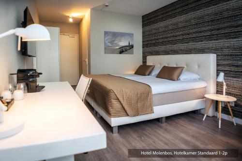 a bedroom with a large bed and a table at Hotel Molenbos Texel in De Cocksdorp