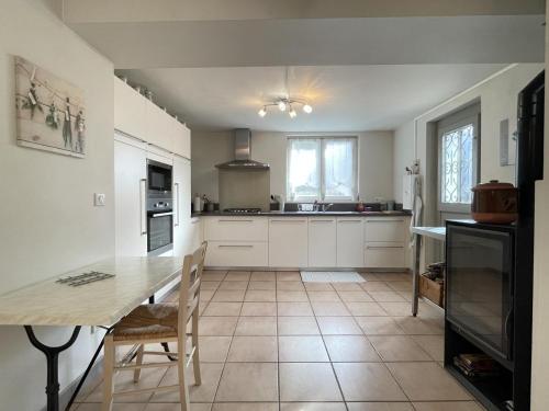 a kitchen with white cabinets and a table with chairs at Gite des cols in Aydius