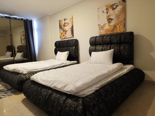 two beds in a room with black furniture at شقة على النيل مباشر بالمعادى 3 غرف الدور 31 فيو الاهرامات in Cairo