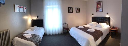 a hotel room with two beds and a window at Hôtel de l'Aviation in La Bourboule