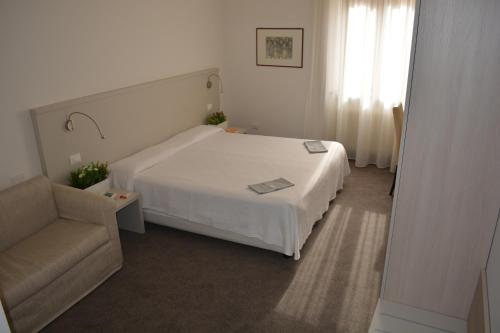 a bedroom with a white bed and a chair at Albergo Accademia in Trento