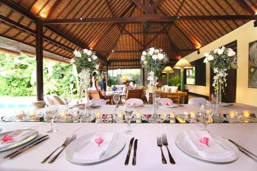 a table with white plates and flowers on top of it at Large Private Villa, central Seminyak, Bali in Seminyak