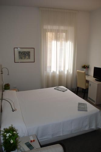 a bedroom with a large white bed with a window at Albergo Accademia in Trento