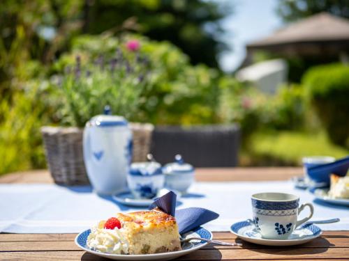 a table with a piece of cake and cups on it at Boutiquehotel Seiler Hof Keitum in Keitum