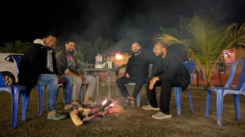 a group of men sitting around a fire at night at Chanaka Eco Camp ( Adventure Assam ) in Pakariāmukh