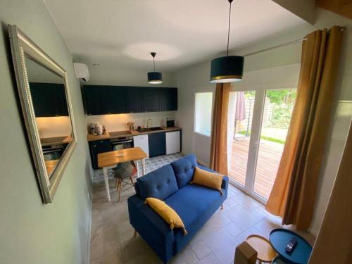 a living room with a blue couch and a kitchen at Le Cast'L 2 Coin de paradis en bord de Dordogne in La Rivière