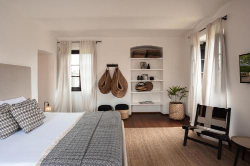 a bedroom with a large white bed and a chair at Les Arcs in Agrate Conturbia