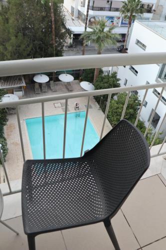 a black chair sitting on a balcony with a swimming pool at Sunflower Hotel Apartments in Larnaka