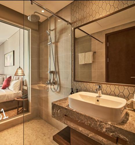 a bathroom with a sink and a shower and a bed at Apec MANDALA CHAM BAY MUI NE SPA RESORT AND CONDOTEL in Ấp Thiẹn Ái
