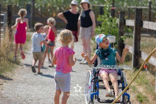 a young girl in a wheelchair and a group of children at Hoeve Megusta in Vlimmeren