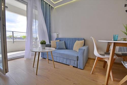 a living room with a blue couch and a table at Sun Towers - Apartamenty Bryza - Apartamenty z parkingiem in Świnoujście