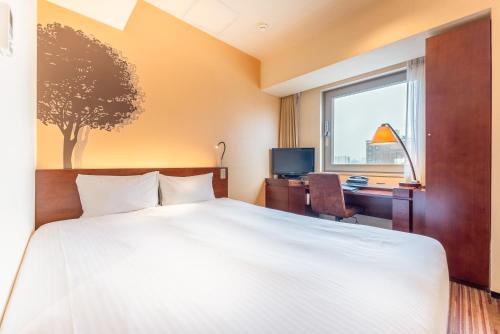 a bedroom with a bed and a desk and a window at Hotel Keihan Asakusa in Tokyo