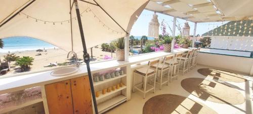 a bar with a view of the beach and an umbrella at Beach penthouse with rooftopbar and Starlink WiFi, spectacular 180 degrees ocean view in Santa Maria