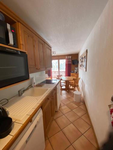 Il comprend une cuisine avec un évier et une télévision murale. dans l'établissement Appartement les Saisies, à Villard-sur-Doron
