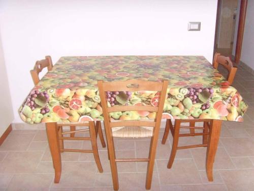 a table with two chairs and a table with fruit on it at Casa Matino in Matino