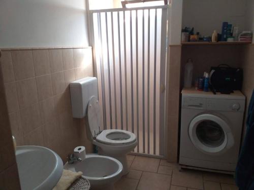 a bathroom with a toilet and a washing machine at Casa Matino in Matino