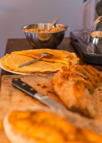 a table with a cutting board with bread and a knife at Maison L'Aiguille - 2 appartements, 5 chambres et table d'hôtes au pied de la montagne à la station de Laye in Laye