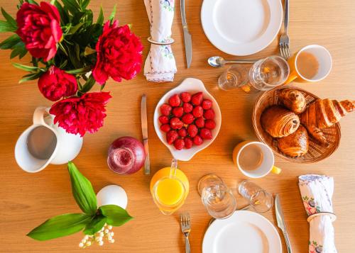 a table with a breakfast of eggs bread and red roses at Maison L'Aiguille - 2 appartements, 5 chambres et table d'hôtes au pied de la montagne à la station de Laye in Laye