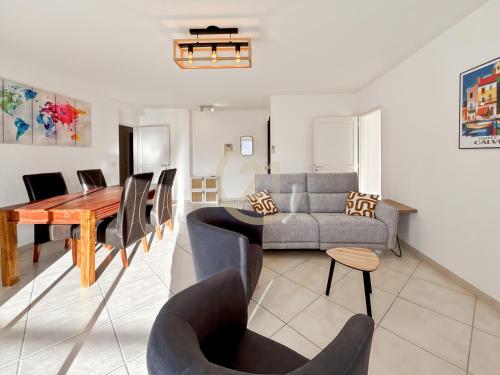 un salon avec un canapé, une table et des chaises dans l'établissement Résidence Port Calvi - Appartement T3 vue mer !, à Calvi