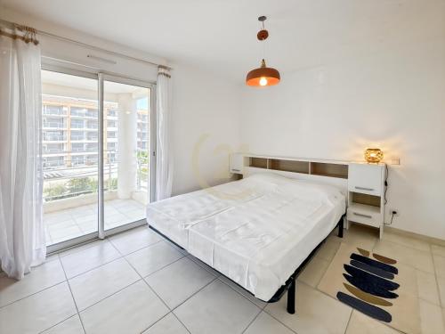 une chambre blanche avec un lit et une grande fenêtre dans l'établissement Résidence Port Calvi - Appartement T3 vue mer !, à Calvi