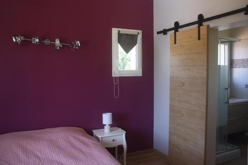 une chambre violette avec un lit et une fenêtre dans l'établissement Bastide provençale avec piscine privée, à Sainte-Cécile-les-Vignes