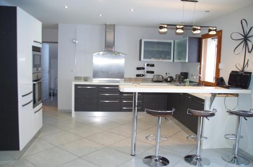 une cuisine avec un comptoir blanc et des tabourets de bar dans l'établissement Maison de village à 5 minutes de St Lary Soulan, à Saint-Lary-Soulan