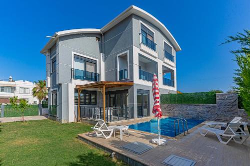 a house with a swimming pool and an umbrella at Villa Tosun in Belek