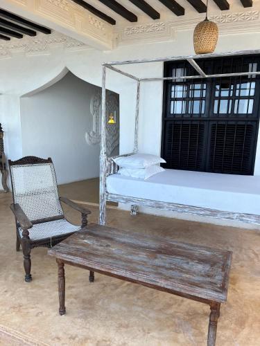a bedroom with a bed and a bench and a chair at Stopover Guest House and Restaurant in Lamu