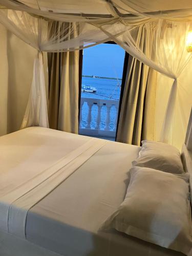 a bedroom with a bed with a view of the ocean at Stopover Guest House and Restaurant in Lamu