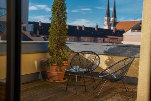 two chairs and a table on a balcony with a tree at Penthouse mit Whirlpool, Sauna, Dachterrasse und Schwedenofen, air-condition in Altötting