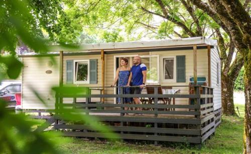 un homme et une femme debout devant une petite maison dans l'établissement mobilhome terrasse ombragée 27m2, à Cahuzac-sur-Vère