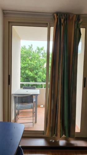 Une porte coulissante en verre s'ouvre sur un balcon avec une table. dans l'établissement Studio 2 pers à 50 m de la plage, à Fleury