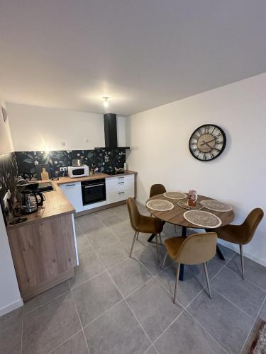 une cuisine avec une table et des chaises et une horloge au mur dans l'établissement Le champs de mars, à La Rochelle