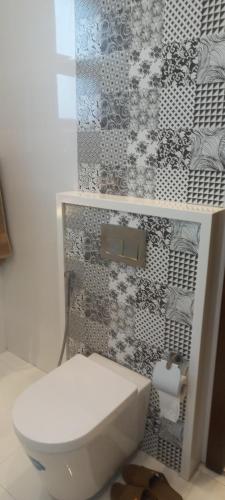 a bathroom with a white toilet and a patterned wall at Oasis Suits DHA in Lahore
