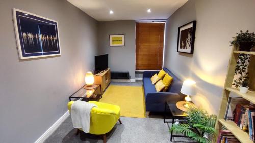 a living room with a blue couch and a yellow chair at West Kirby Apartment in West Kirby