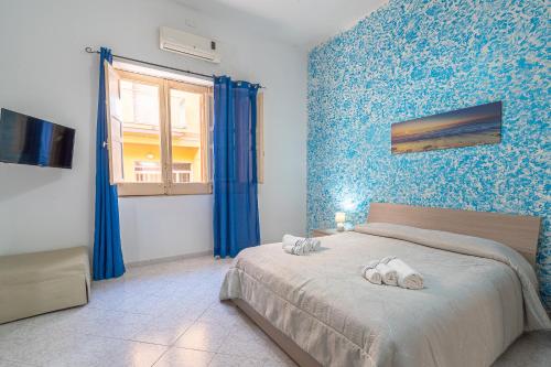 a bedroom with a large bed with blue walls at Sea House a due passi dal mare in Pozzallo