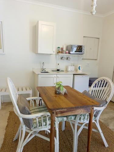 a kitchen with a wooden table and white chairs at Maison H Guest House in Durban