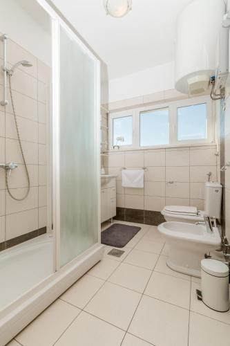 a white bathroom with a shower and a toilet at Villa Comfort in Kaštela