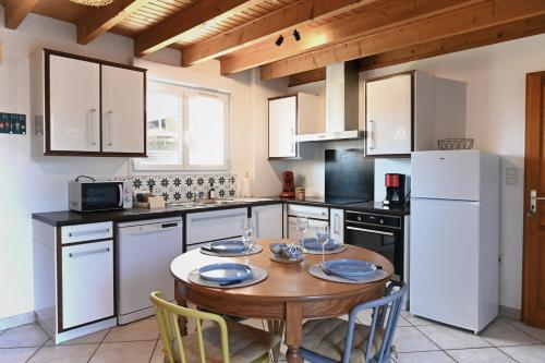 une cuisine avec une table en bois et des appareils électroménagers blancs dans l'établissement Les Roses Trémières - A 1km de la gare garage, à Saujon