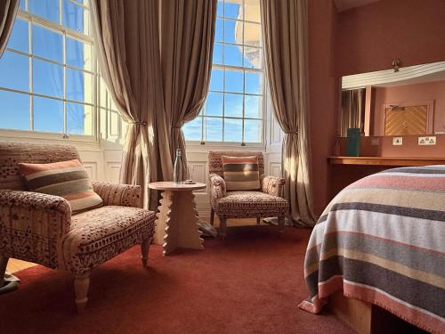 a bedroom with a bed and two chairs and a window at Drakes Hotel in Brighton & Hove