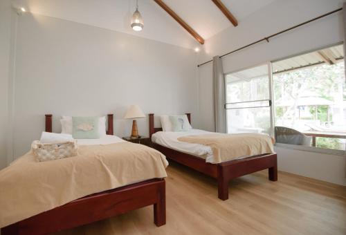 a bedroom with two beds and a large window at Seashell Village Resort in Chao Lao Beach