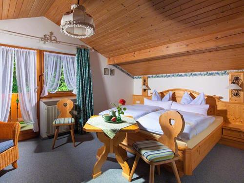 a bedroom with a bed and a table and chairs at Pension Waldklause in Schönau am Königssee