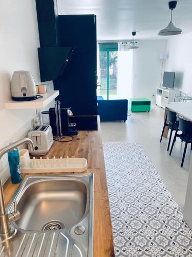 une cuisine avec un évier en acier inoxydable dans l'établissement Charmante petite maison, à Hourtin